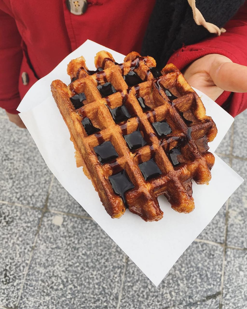 Waffle belga al cioccolato servito su tovagliolo bianco, specialità dolciaria tipica.